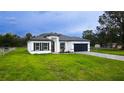 Attractive single-story home featuring a manicured lawn, modern design, and a dark garage door at 16734 Sw 18Th Avenue Rd, Ocala, FL 34473