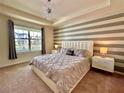 Luxurious main bedroom featuring tray ceiling, modern lighting, and large windows at 2034 Fleming Mist Pl, Kissimmee, FL 34747