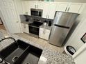 Modern kitchen with stainless steel appliances, white cabinets, granite countertops, and black hardware, offering a sleek design at 2778 Almaton Loop # 302, Kissimmee, FL 34747