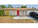 Close up of single-story home with a red front door and driveway with a vehicle parked in front at 3711 Shady Grove Cir, Orlando, FL 32810