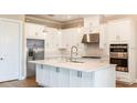 Well-lit kitchen featuring white cabinets, a large island, stainless steel appliances, and stylish pendant lights at 4204 Barbuda Ln, Kissimmee, FL 34758