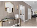 Elegant hallway featuring a stylish gold mirror, glass console table, and a peek into the powder room at 4375 Scene Ln, Kissimmee, FL 34746