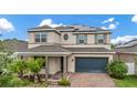 Inviting two-story home with a brick driveway, complemented by lush landscaping and solar panels at 4783 Riverwalk Dr, St Cloud, FL 34771