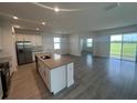 Open-concept kitchen boasts an island, stainless steel appliances, and tile flooring flowing into the living space at 7116 Cherry Pasture Rd, Groveland, FL 34736