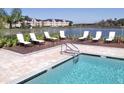 Community swimming pool with lounge chairs and lake view at 7606 Pissarro Dr # 14206, Orlando, FL 32819