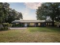 Well-maintained one-story brick house featuring a metal roof, manicured lawn, and mature trees in a serene setting at 949 Shadow Oaks Rd, Kissimmee, FL 34744