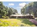 Sprawling brick home with mature trees and a metal roof offers curb appeal and character at 949 Shadow Oaks Rd, Kissimmee, FL 34744