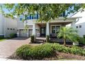Two-story home with brick driveway and walkway leading to a covered front porch and lush landscaping at 15420 Southern Martin St, Winter Garden, FL 34787