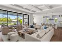 Bright living room featuring stylish seating, coffered ceiling, and sliding glass doors overlooking a beautiful lake at 1891 Lake Spier Dr, Winter Park, FL 32789