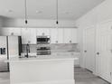 Modern kitchen with stainless steel appliances, white cabinets, a central island, and stylish pendant lighting at 2333 Sw 147Th Pl Rd, Ocala, FL 34473