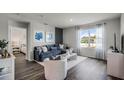 Stylish living room with hardwood floors, a comfortable blue sofa, and large windows offering natural light at 3715 Bluethread Way, Poinciana, FL 34759