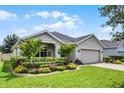 Inviting single-story home featuring a well-maintained lawn, mature landscaping, and a brick driveway at 4051 Prairie Reserve Blvd, Orlando, FL 32824