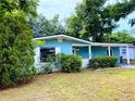 Quaint single-story home with a white picket fence, lush greenery, and a freshly painted blue exterior at 605 Pleasantdale Dr, Wildwood, FL 34785