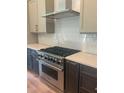 Modern kitchen features stainless steel appliances, gray backsplash, and gray cabinets at 6125 Village Edge Pl, Sanford, FL 32771