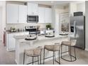 Modern kitchen with white cabinetry, stainless steel appliances, granite countertops, and bar seating at 674 Pennywort St, Lake Alfred, FL 33850