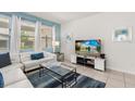 Bright living room with large TV and cozy white sectional sofa at 7041 Oakwood St, Davenport, FL 33837