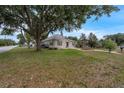 View of the home showing a large front yard with mature trees, well-kept lawn, and a decorative fountain at 803 Jersey Ave, St Cloud, FL 34769
