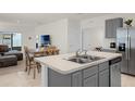 Modern kitchen features stainless steel appliances, gray cabinets, and an island with a sink at 1323 Berry Ln, Davenport, FL 33837