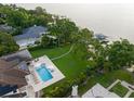 Aerial view of a property with a pool, manicured lawn, and lake access with a private dock at 1455 Kelso Blvd, Windermere, FL 34786