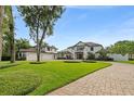 Elegant home with a brick driveway, manicured lawn, and a three-car garage on a sunny day at 1455 Kelso Blvd, Windermere, FL 34786