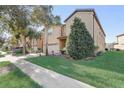 Side exterior shot of a two-story home with lush landscaping and a well-maintained lawn, with palm trees and beautiful shrubbery at 2186 Tripoli Ct, Kissimmee, FL 34747