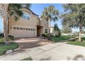 Lovely front exterior of a two-story home with a brick driveway, manicured lawn, and mature landscaping including palm trees at 2186 Tripoli Ct, Kissimmee, FL 34747