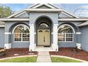 Inviting home entrance featuring a covered porch, double doors, and arched windows with decorative shutters at 394 Hickory Springs Pl, Debary, FL 32713