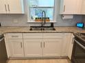 Well-lit kitchen with white cabinets, granite countertops, stainless steel sink, and a decorative window at 415 Seville Ave, Altamonte Springs, FL 32714
