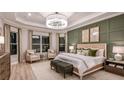 Beautifully staged main bedroom featuring a tray ceiling, elegant chandelier, wainscoting, and ample natural light at 5658 Nevis Ter, Kissimmee, FL 34758