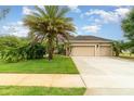 Charming single-story home featuring a fountain, a well-manicured lawn, and an attached two-car garage at 611 Curly Fern Ln, Deland, FL 32720