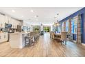 Open-concept kitchen and dining area with white cabinets, breakfast bar, and modern light fixtures at 7647 Fairfax Dr, Kissimmee, FL 34747