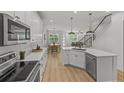 Open-concept kitchen with white cabinets, quartz countertops, stainless appliances, and views of the dining and living area at 1002 Farmstead St, Eustis, FL 32736