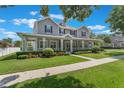 Charming two-story home featuring a spacious front porch, manicured lawn, and beautiful landscaping at 10100 Loblolly Pine Cir, Orlando, FL 32827