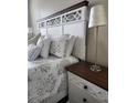 Bright bedroom features an elegant white headboard, patterned bedding, and a stylish nightstand with a table lamp at 3500 Calabria Ave, Davenport, FL 33897