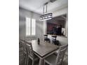 Well-lit dining area features a wooden table with seating for six, a modern chandelier, and a view of the kitchen at 3500 Calabria Ave, Davenport, FL 33897