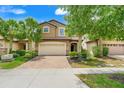 Charming home featuring a two-car garage, lush landscaping, and a brick driveway at 8989 Rhodes St, Kissimmee, FL 34747