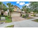 Attractive home featuring a two-car garage, brick driveway, and meticulously maintained landscaping at 8989 Rhodes St, Kissimmee, FL 34747