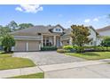 Beautiful home with a lush green lawn and landscaping in front of a three car garage at 13137 Lower Harden Ave, Orlando, FL 32827