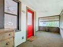 Enclosed porch with white wainscoting, a red door, and several windows providing natural light at 1511 New York Ave, St Cloud, FL 34769