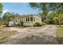 View of the side of the house with gravel driveway and mature trees at 2229 N 6Th St, Orlando, FL 32820