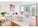 Bright living room featuring hardwood floors, white furniture, and city views from a large window at 322 E Central Blvd # 1612, Orlando, FL 32801