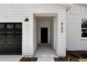 Inviting front entrance featuring a modern front door, dark garage door, and house number 6106 at 6106 Sw 127 Avenue Rd, Ocala, FL 34481