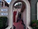 View of building entrance with an arched walkway and red stairs leading to the upper units at 7858 Sugar View Ct # 7858, Orlando, FL 32819
