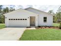 A lovely one-story white home featuring a two-car garage, verdant lawn, and eye-catching curb appeal at 8258 Sw 136Th Ter, Dunnellon, FL 34432