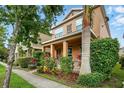 Inviting two-story home with a covered porch and lush tropical landscaping at 9389 Meadow Hunt Way, Winter Garden, FL 34787