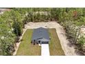 New single-story home with a gray roof, long driveway and a spacious treed yard at 9695 Sw 125 Court Rd, Dunnellon, FL 34432