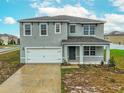 Two-story home featuring a gray exterior, a two-car garage, and a covered front porch at 979 Sun Burst Rd, Winter Haven, FL 33880