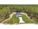 New construction home surrounded by lush greenery, a long driveway, and plenty of land at 12197 Sw 76 Ln, Dunnellon, FL 34432