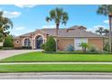 Attractive single-story home featuring beautiful landscaping with palm trees, green lawn and a brick driveway at 13524 Glynshel Dr, Winter Garden, FL 34787