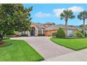 Stunning single-story home with lush landscaping and a winding brick driveway leading to a welcoming entrance at 13524 Glynshel Dr, Winter Garden, FL 34787